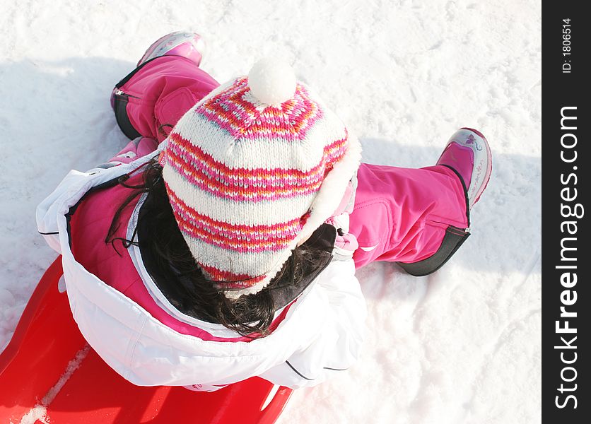 Young girl in colorful ski clothing takes a break from sledding. Young girl in colorful ski clothing takes a break from sledding