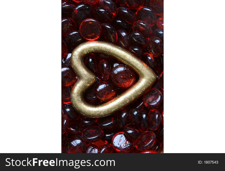 Gold heart lying on red glass beads
