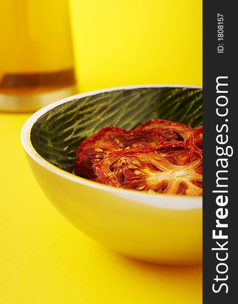 Dried sliced tomatoes in green bowl on the yellow background. Dried sliced tomatoes in green bowl on the yellow background.