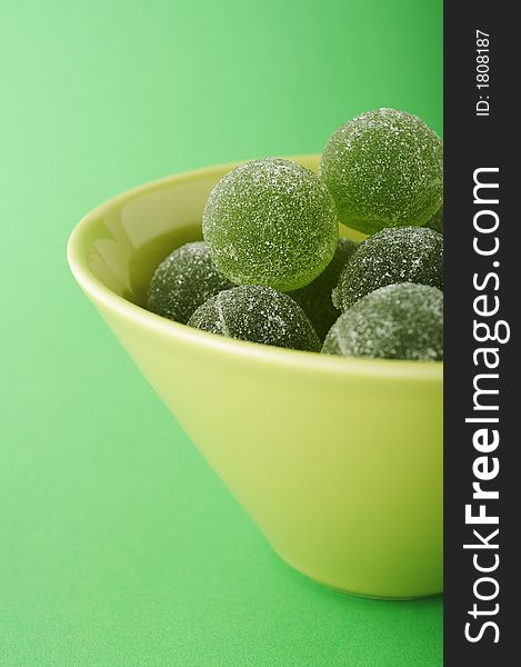 Green marmalade balls in the bowl on the green background