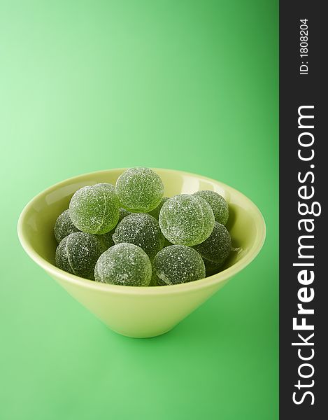 Green marmalade balls in the bowl on the green background