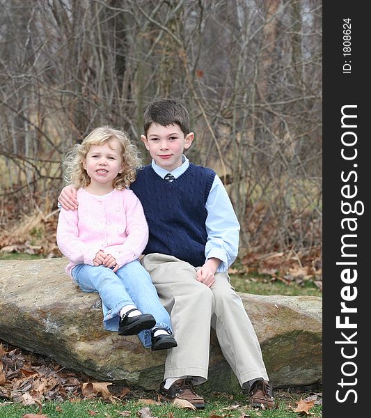 Happy young children siblings in park like setting on rocks. Happy young children siblings in park like setting on rocks.