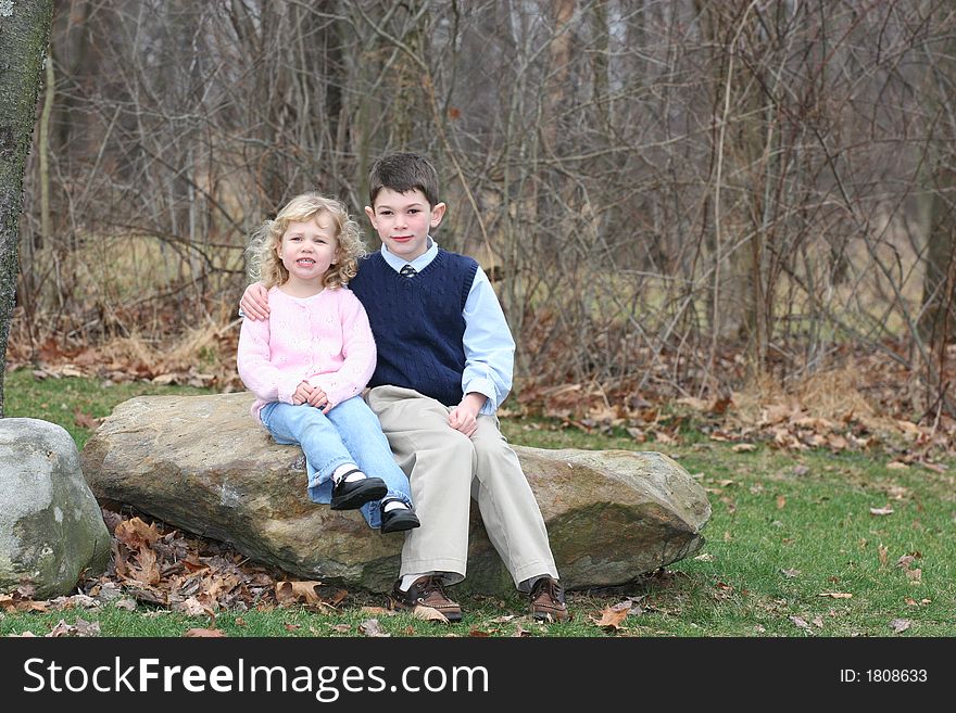 Happy young children siblings in park like setting on rocks. Happy young children siblings in park like setting on rocks.