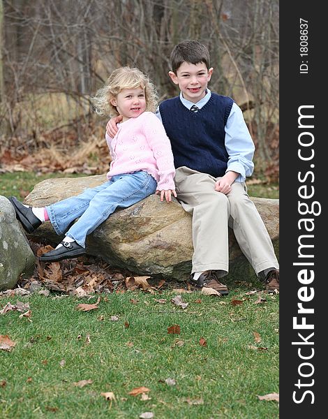 Happy young children siblings in park like setting on rocks. Happy young children siblings in park like setting on rocks.