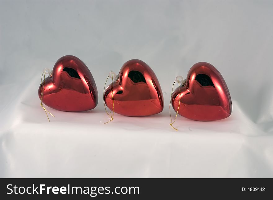 Three shinny heart shaped ornaments lined up on a white background. Three shinny heart shaped ornaments lined up on a white background.