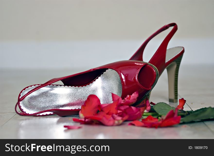 Red high-healed shoes left on the floor next to a crushed rose implying an evening that ended in disappointment. Red high-healed shoes left on the floor next to a crushed rose implying an evening that ended in disappointment