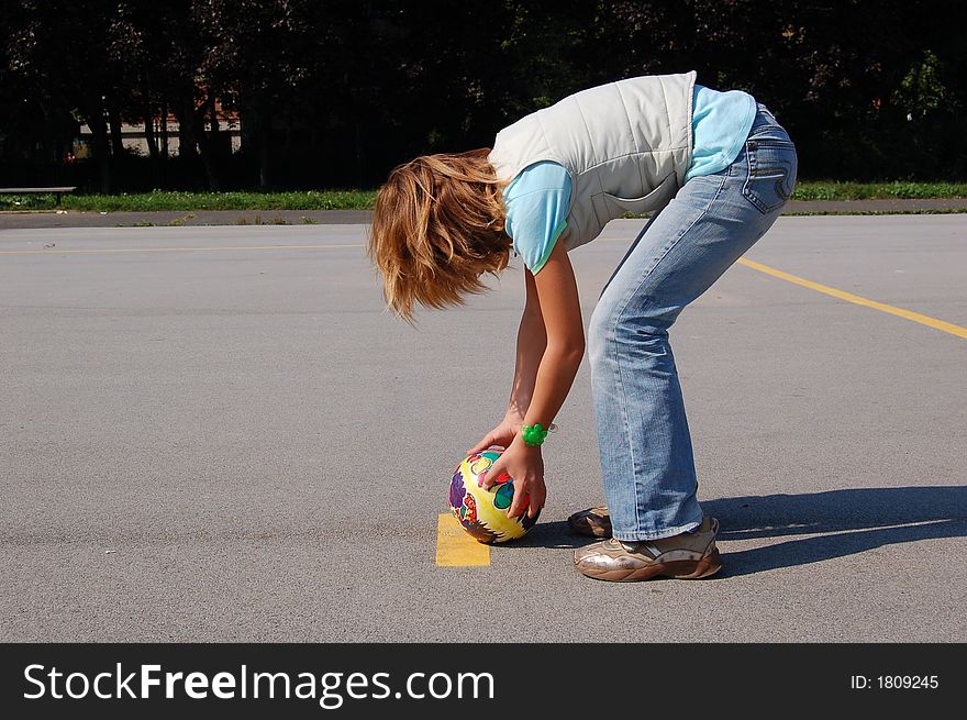 Teenage girl on a playground preparing to kick the ball. Teenage girl on a playground preparing to kick the ball.