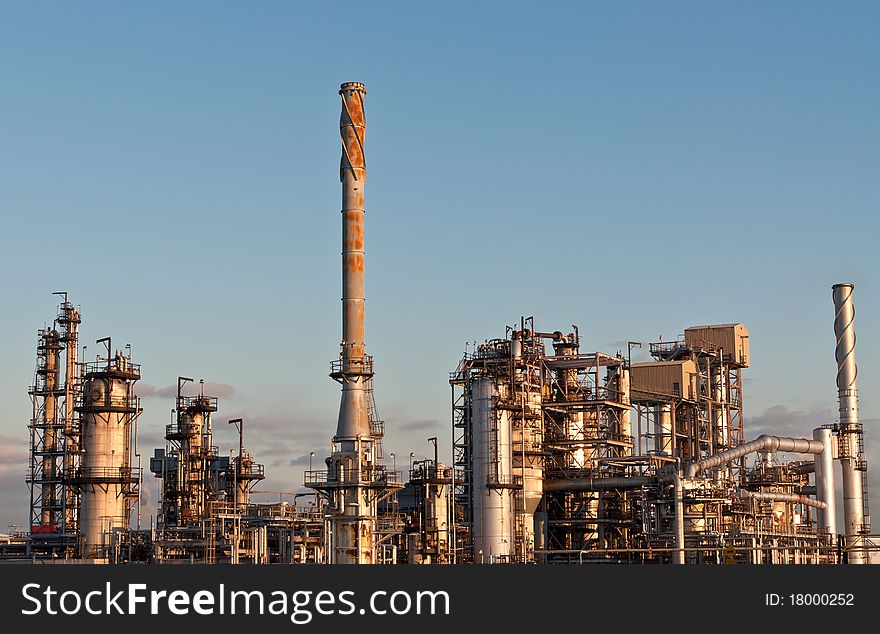 A petrochemical refinery plant with pipes and cooling towers. A petrochemical refinery plant with pipes and cooling towers.