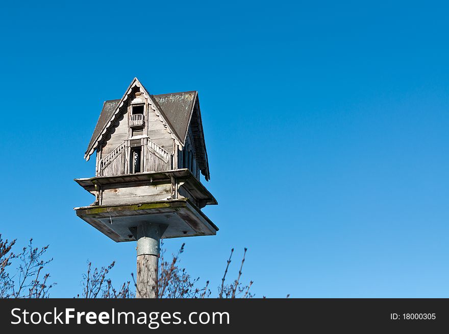 A birdhouse sits atop a pole with a deep blue sky in the background. A birdhouse sits atop a pole with a deep blue sky in the background.