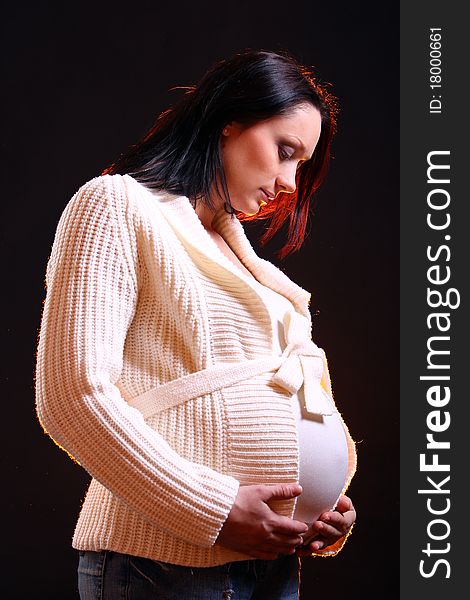 Young and beautiful pregnant woman on black background with smoke