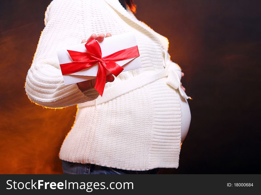 Young and beautiful pregnant woman on black background with smoke