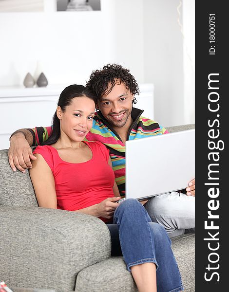 Smiling couple on a sofa with laptop