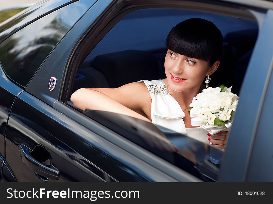 Happy bride with flower bouquet siting in the car. Happy bride with flower bouquet siting in the car