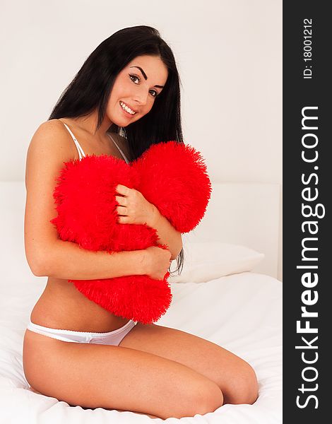 Beautiful brunette woman at home hugging a big fluffy soft heart. feast day of St. Valentine