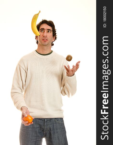 Young man juggling fruit in a white background. Young man juggling fruit in a white background