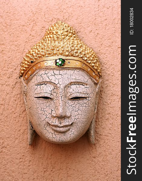 Handcrafted wooden buddha face decorative mask on yellow background