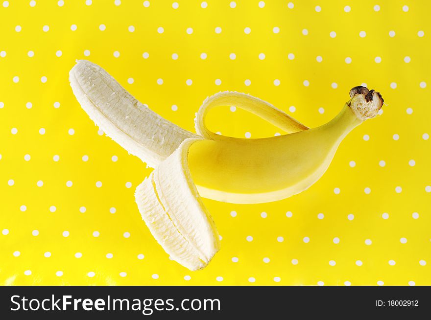 Ripe peeled banana on yellow polka dot background. Ripe peeled banana on yellow polka dot background