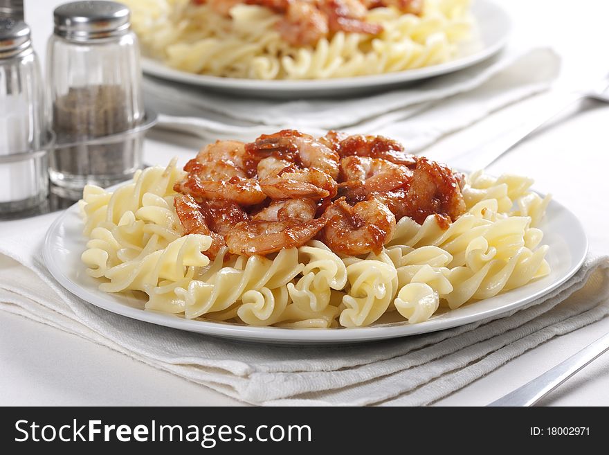 Two plates of pasta with tomato and prawns