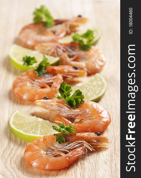 Shrimps on board with parsley and lemon wedges. Shrimps on board with parsley and lemon wedges