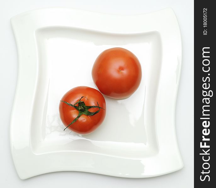 Two tomatoes on white plate-top view. Two tomatoes on white plate-top view.