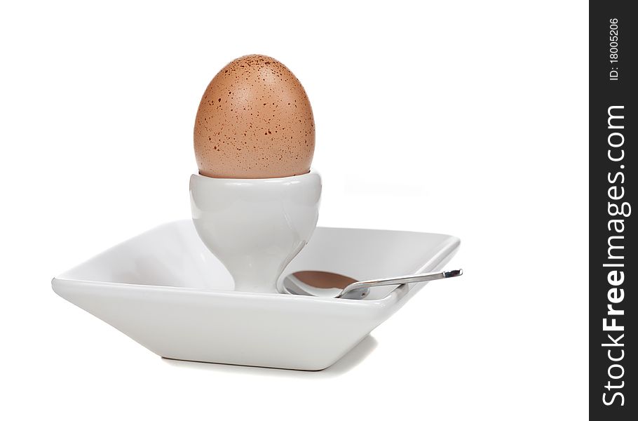 A free-range boiled egg in a dish with a spoon. White background. A free-range boiled egg in a dish with a spoon. White background.