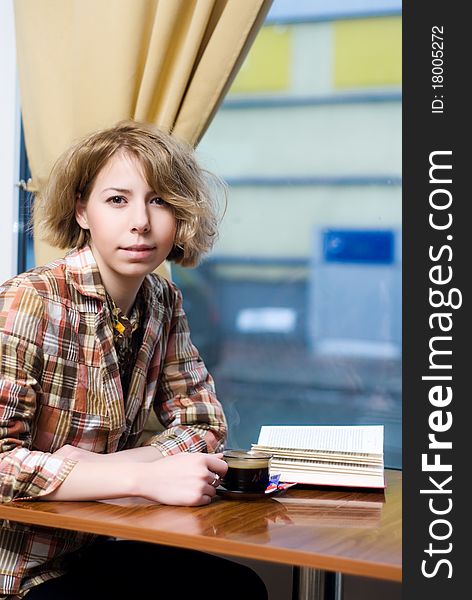 Sensual girl reading a book and drinking a coffee in a coffee shop. Sensual girl reading a book and drinking a coffee in a coffee shop