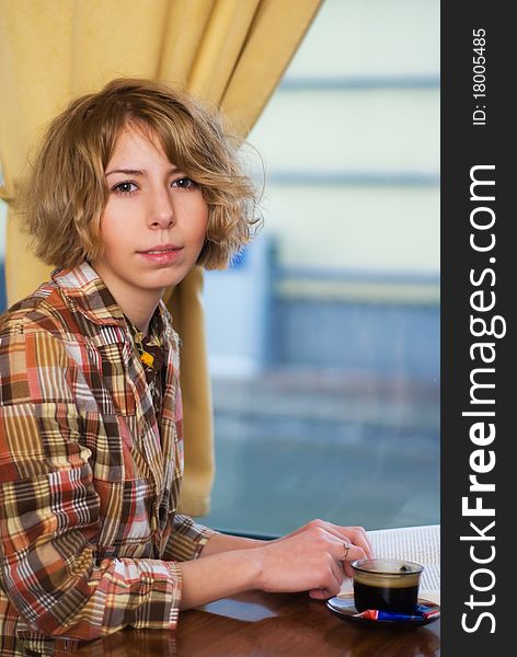 Sensual girl reading a book and drinking a coffee in a coffee shop. Sensual girl reading a book and drinking a coffee in a coffee shop