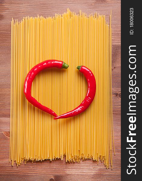 Two red hot chili peppers as a heart on the italian spaghetti. Two red hot chili peppers as a heart on the italian spaghetti
