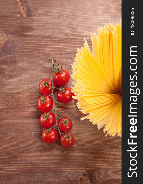 Bunch of spaghetti on a wooden table with cherry tomato. Bunch of spaghetti on a wooden table with cherry tomato