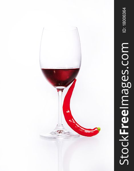 Glass of red wine with red hot chili pepper over white. Glass of red wine with red hot chili pepper over white