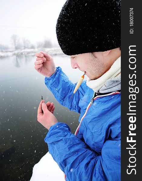 Image of a young fisherman preparing his fishing rod in winter time. Image of a young fisherman preparing his fishing rod in winter time