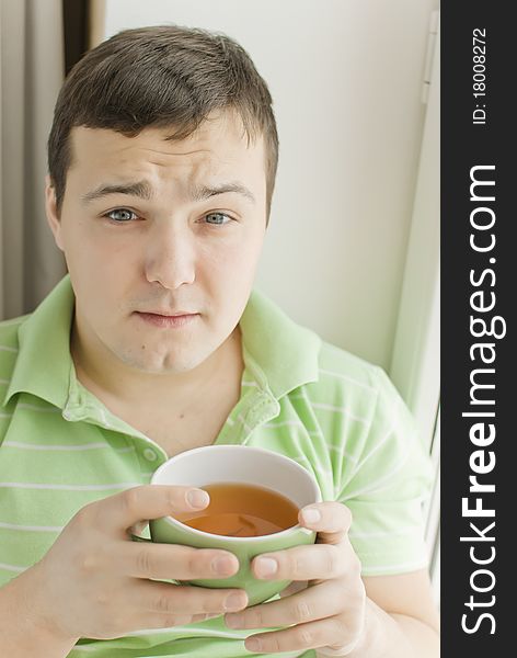 Young man drinking tea on a windowsill