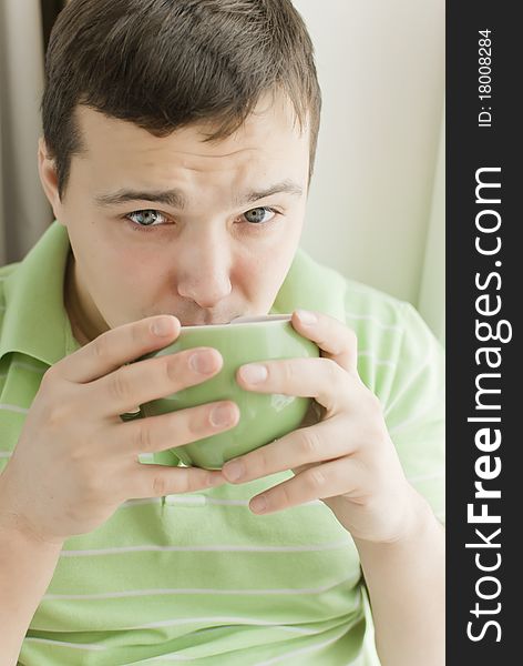 Young man drinking tea on a windowsill