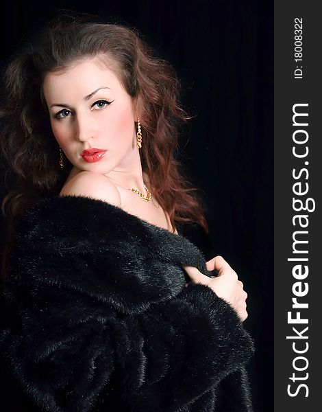 Beautiful young woman in a black fur coat and jewelry. Beautiful young woman in a black fur coat and jewelry
