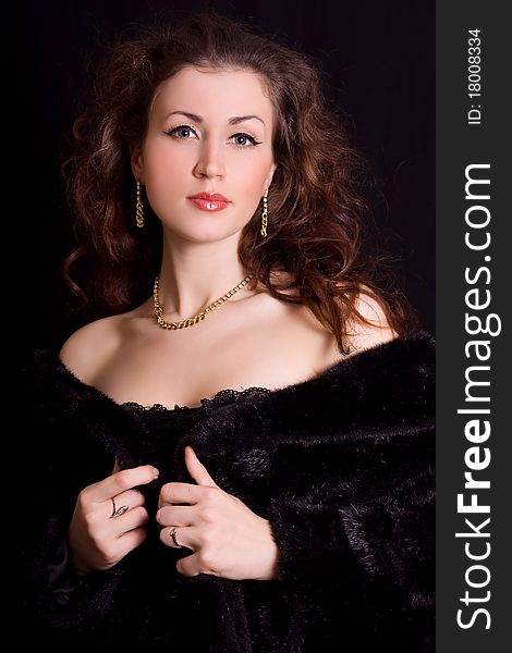 Beautiful young woman in a black fur coat and jewelry