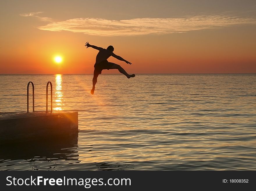 A man jumping into sea at sunset. A man jumping into sea at sunset
