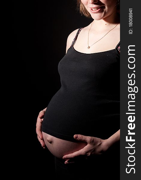 Beautiful pregnant woman staing on black background