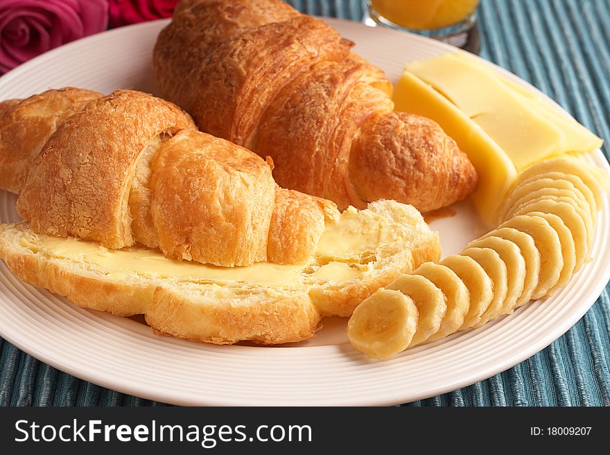 Breakfast plate with freshly baked croissants with butter, cheese and sliced bananas. Breakfast plate with freshly baked croissants with butter, cheese and sliced bananas