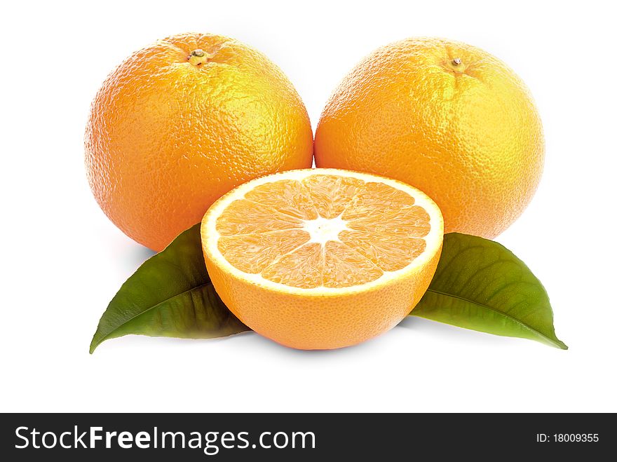 Three juicy oranges and green leaves on a white background. Three juicy oranges and green leaves on a white background