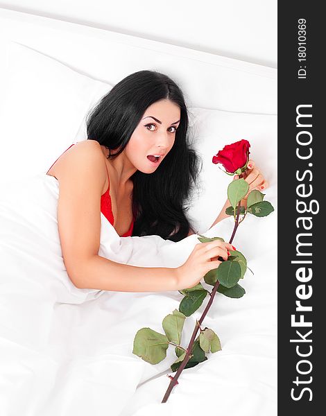 Beautiful brunette woman wakes up and discovers a rose in her bed. Beautiful brunette woman wakes up and discovers a rose in her bed