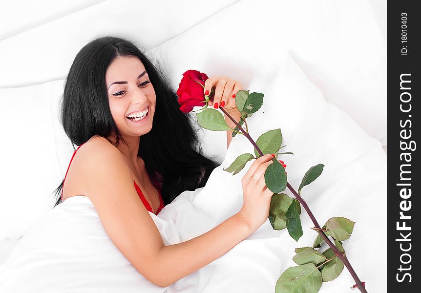 Beautiful brunette woman wakes up and discovers a rose in her bed. Beautiful brunette woman wakes up and discovers a rose in her bed