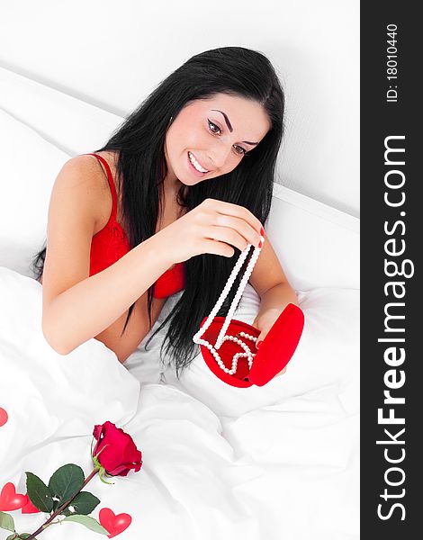 Beautiful brunette woman waking up at home with presents and a rose near her, prepared by her husband. Beautiful brunette woman waking up at home with presents and a rose near her, prepared by her husband