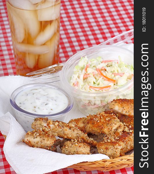 Chicken strips with coleslaw and sauce in a basket with a drink