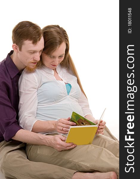 Young couple expecting their first child looking through a childrens book. Young couple expecting their first child looking through a childrens book