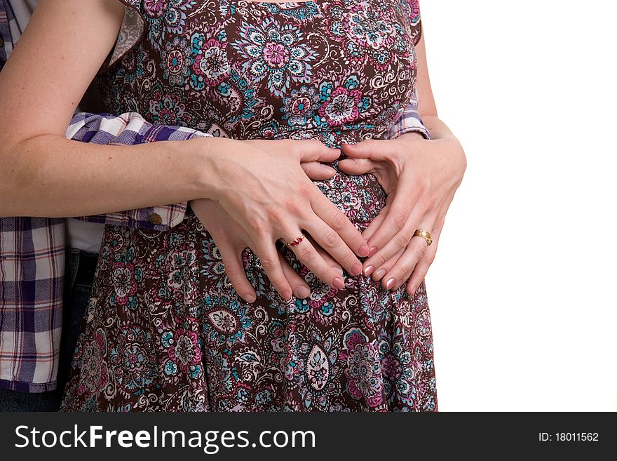 A young couple expecting their first child - hands held in shape of heart of her belly.