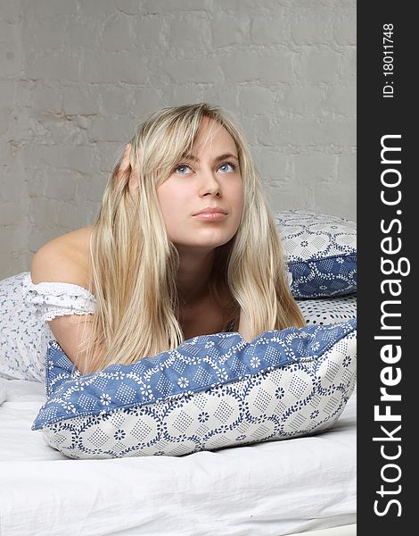 Beautiful blond woman lying in bed and looking up. Gentle morning light. Beautiful blond woman lying in bed and looking up. Gentle morning light