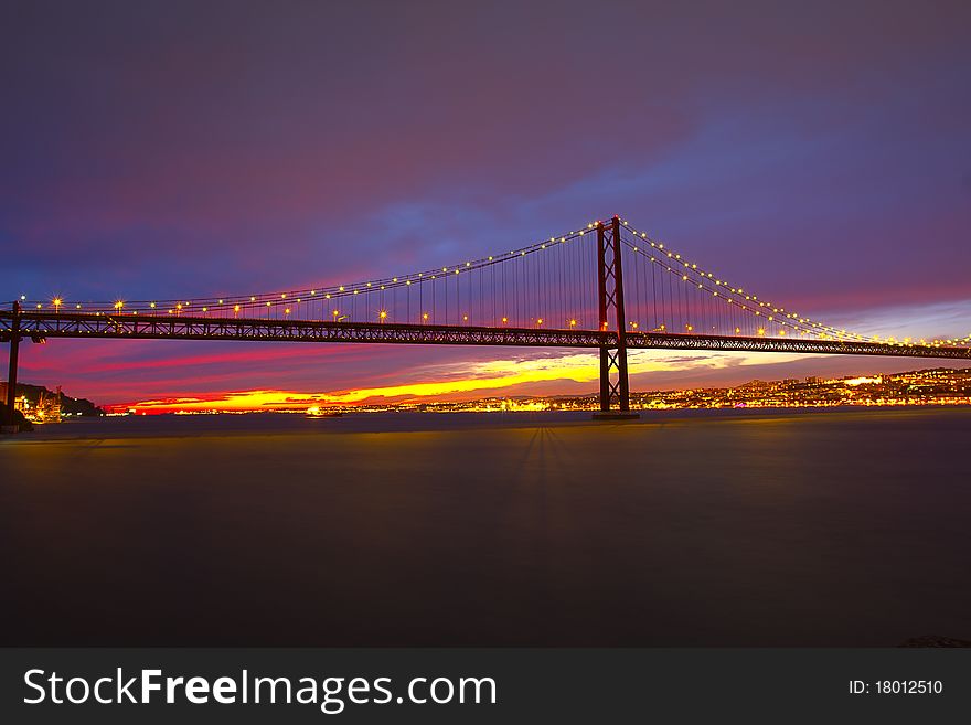 The 25 de Abril Bridge - suspension bridge over the river Tagus illuminated at night. Lisbon Portugal. The 25 de Abril Bridge - suspension bridge over the river Tagus illuminated at night. Lisbon Portugal