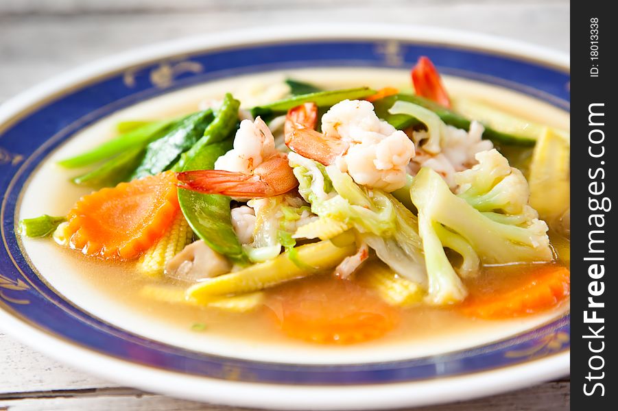 A dish of asian food included with mixed vegetable and shrimp.