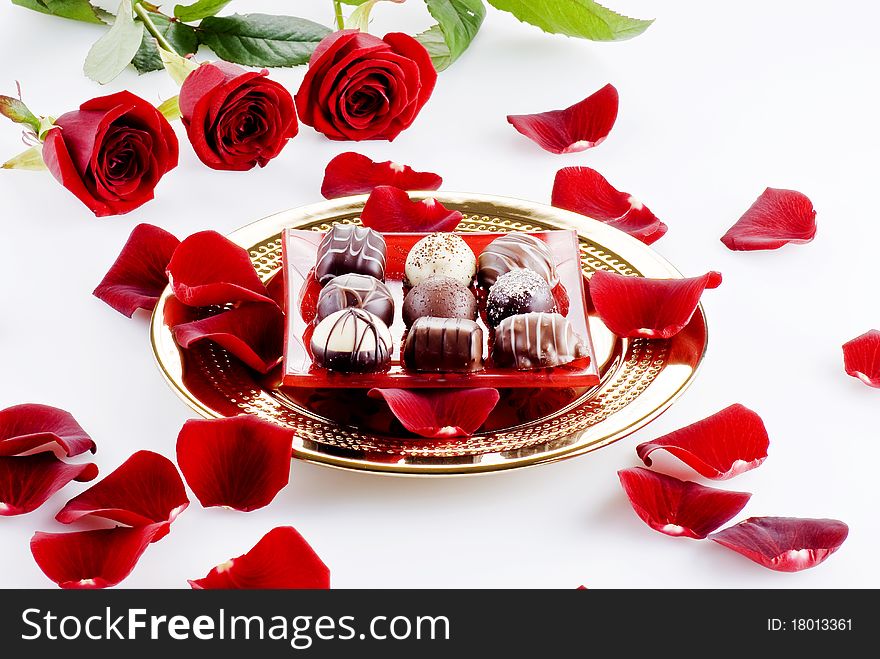 Gold plate of luxury chocolates with red roses. Gold plate of luxury chocolates with red roses