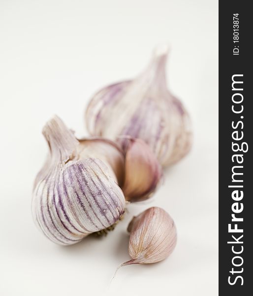 A garlic clove beside two heads of garlic, one open. Shallow depth of field. A garlic clove beside two heads of garlic, one open. Shallow depth of field.